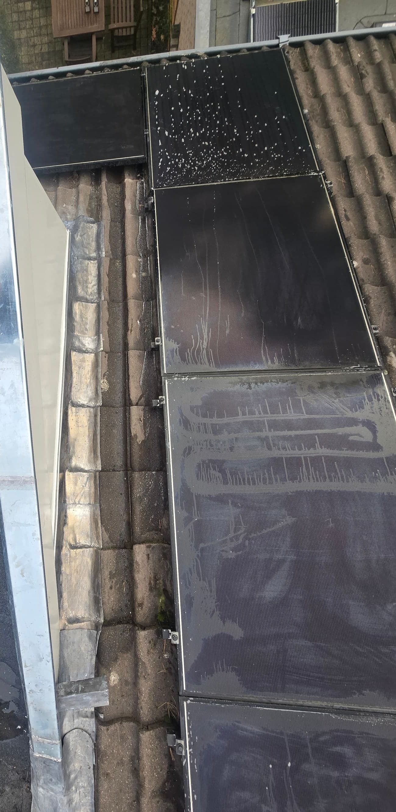 Vernieuwd loodwerk op de overgang van een plat dak naar een pannendak met zonnepanelen