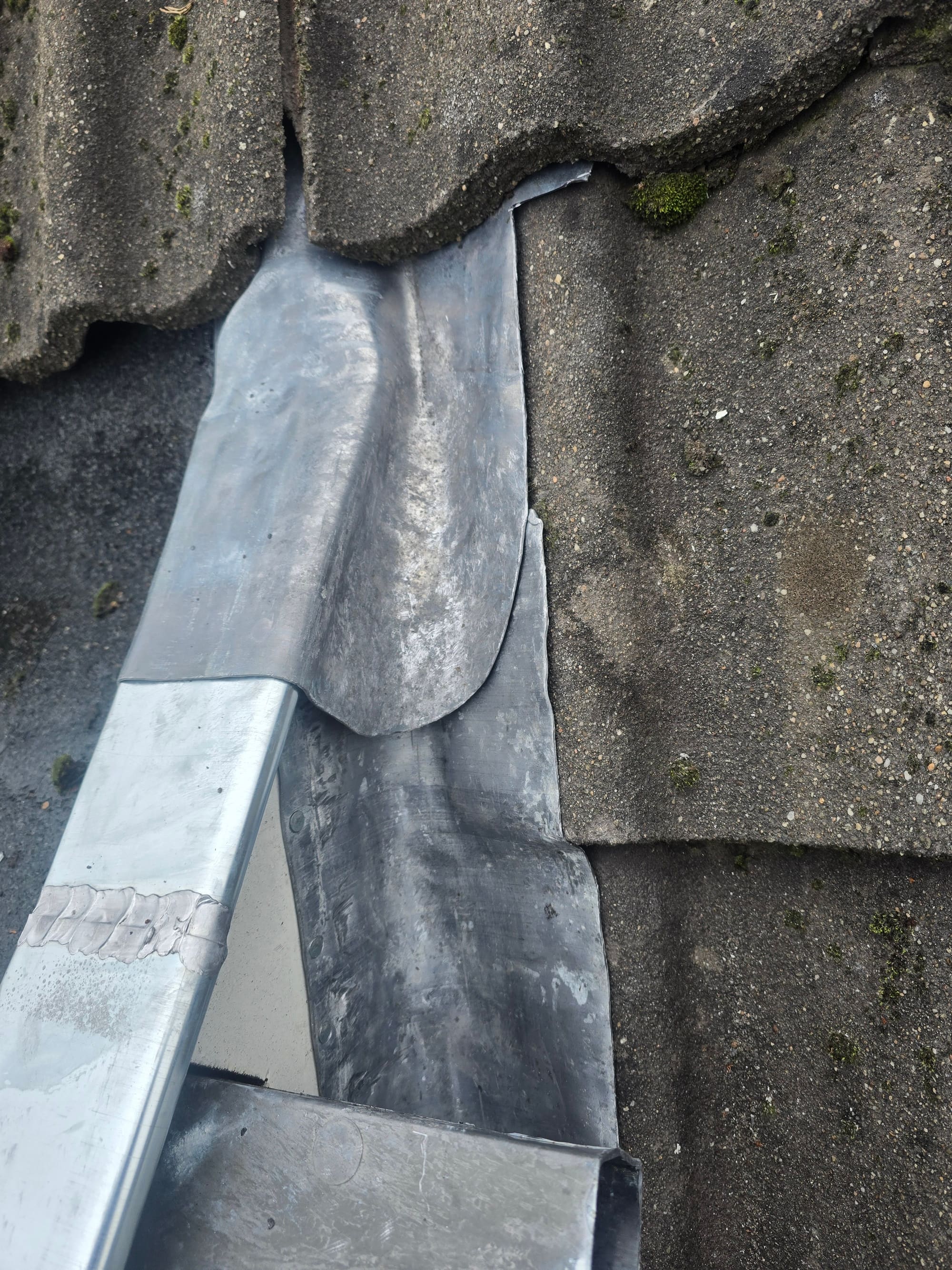 Met de hand gezet loodwerk tussen dakpannen en een zinken goot