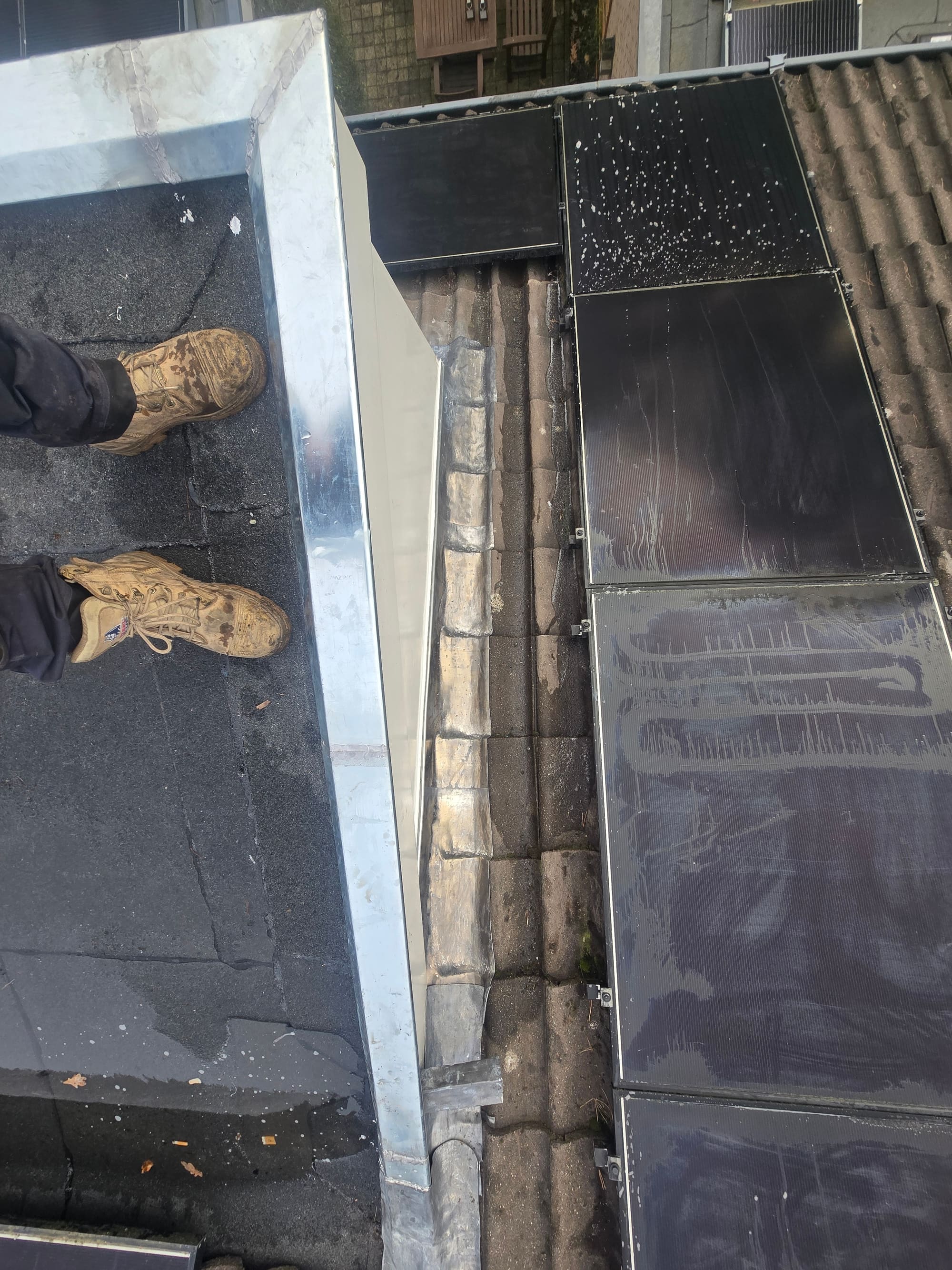 Zink- en loodwerk op de overgang van een plat dak naar een pannendak met zonnepanelen